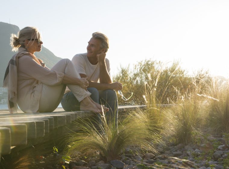 Couple relax on boardwalk, at lakeshore